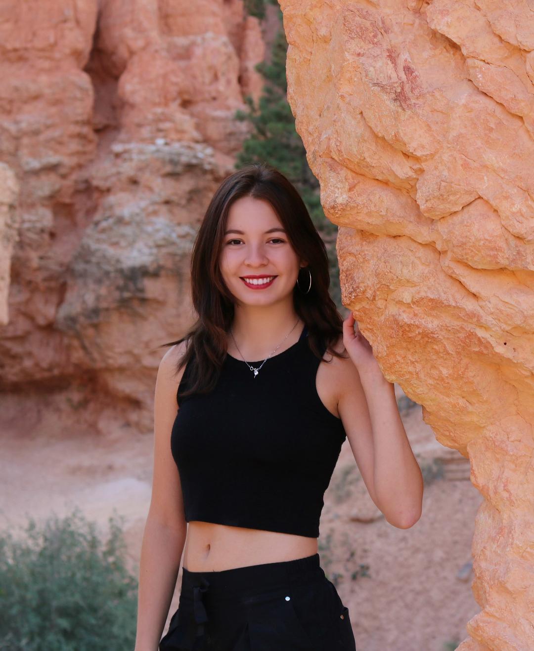 Student posing in front of a scenic cave