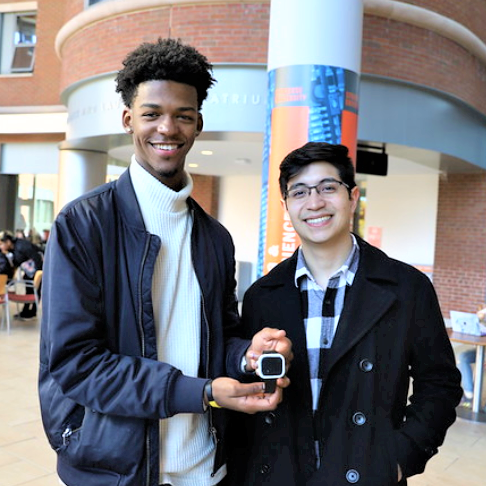 two students holding their prototype of a smart watch device