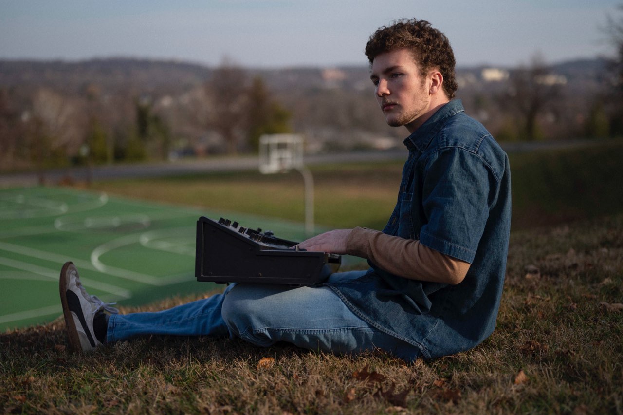 student sitting in a field with a soundboard